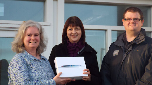 Hazel Shearer drops into the office to collect her prize from the Associations Housing Manager Fiona Robertson and the Chief Executive Bryan Leask